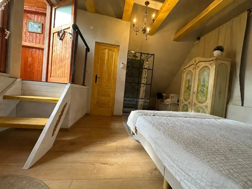 Attic room with a staircase with painted balustrade, a yellow door, a hand-painted wardrobe and a chandelier under the sloped ceiling