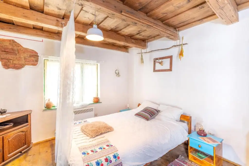 Bright whitewashed bedroom with a timber ceiling, a canopy net over the bed, a patch of exposed brick and a blue-painted nightstand
